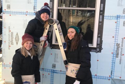 三名妇女穿着冬衣站在梯子上，为仁人家园做志愿者
